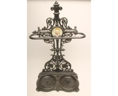 A VICTORIAN CAST IRON STICK STAND, the waisted open work back moulded with foliate scrolls and centred by a portrait medallio