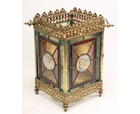 A LATE VICTORIAN GILDED BRASS AND GLASS HALL LANTERN of square form, the leaded stained glass panelled sides centred by a cle
