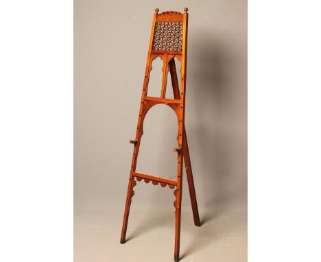 A LATE VICTORIAN MAHOGANY STUDIO EASEL of square tapering form, arched scrolled top rail over pierced and carved Middle Easte
