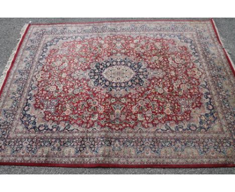 A PAKISTANI KASHAN CARPET, the brick red field with navy blue and ivory central gul and similar spandrels and with all over i