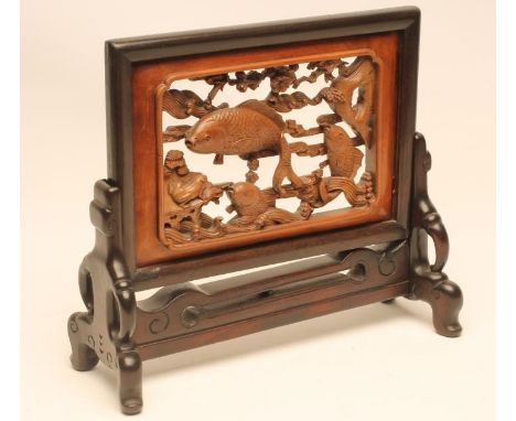 A CHINESE HARDWOOD TABLE SCREEN, the light wood lift-out panel carved and pierced with carp swimming amidst rocks and waves a