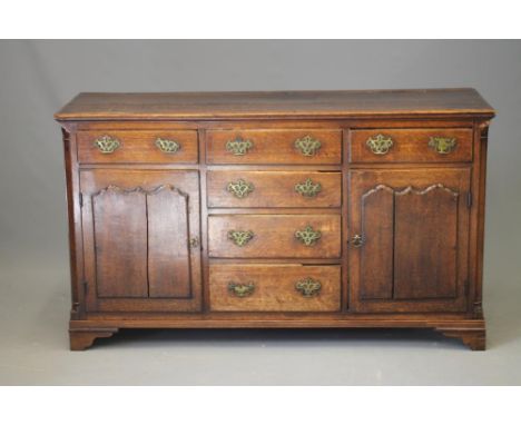 A GEORGIAN OAK ENCLOSED DRESSER, early 19th century, the moulded edged plank top over four central drawers flanked on either 