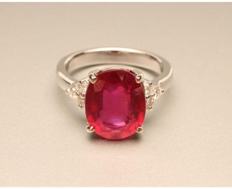 A RUBY RING, the oval facet cut stone of approximately 6cts, claw set to shoulders each with three small round brilliant cut 