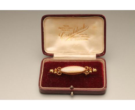 A VICTORIAN OPAL BROOCH, the eliptical cabochon polished stone claw set to a knife edge bar with scroll and bead knops, unmar