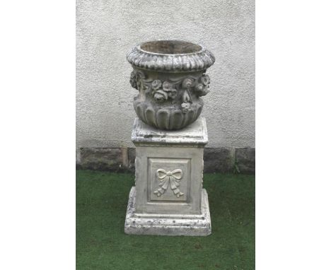 A COMPOSITION STONE URN of waisted half fluted form with ribbon tied floral swags in high relief, (lacking socle and base), o