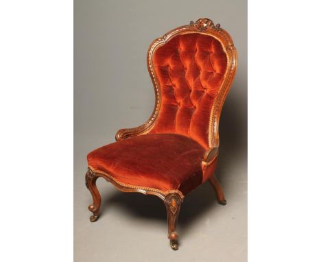 A VICTORIAN WALNUT FRAMED NURSING CHAIR of spoonback form, button upholstered in rust velvet, carved padded back, overstuffed