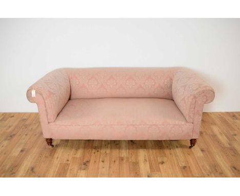 A 19th Century Victorian two person sofa upholstered in pink damask fabric, the scrolled elbow rests flanking the sprung cush