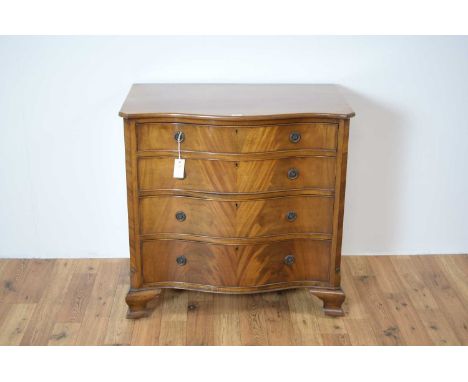 An early 20th Century Georgian style serpentine mahogany chest of drawers, the flared top over four graduated drawers with tw