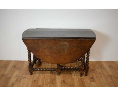 An 18th Century oak drop leaf table, the top with a chamfered edge, raised on bobbin turned gateleg supports and stretchers, 