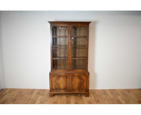 A 20th Century Georgian-style mahogany glazed bookcase, the flared cornice over a double door cabinet with gothic astragal gl