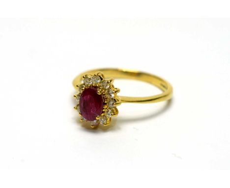 A ruby and diamond cluster ring, the oval facet cut ruby surrounded by twelve brilliant cut diamonds weighing a total of appr
