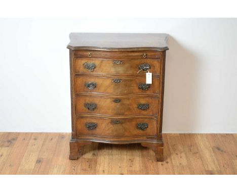 A 1930s Georgian-style serpentine mahogany bachelor's chest of drawers, the flared top with pull-out brushing slide, over fou