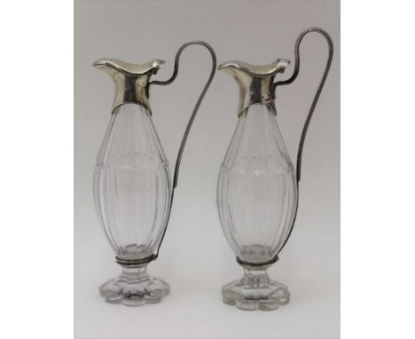 A PAIR OF 19TH CENTURY SILVER MOUNTED CUT GLASS OIL & VINEGAR JUGS, hinged covers with sweeping handles, raised on pearl form