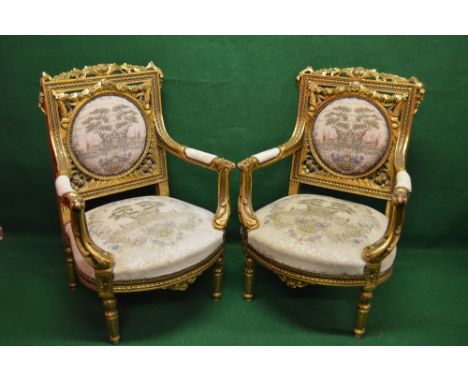 Pair of Louis XV style gilt wood carved armchairs having circular tapestry panel backs, arms and seats, standing on turned re