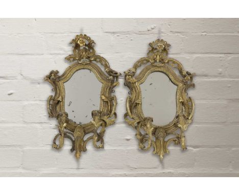 A pair of giltwood girandoles,18th century, Northern European, each cartouche-shaped mirror plate within a foliate scrolled b