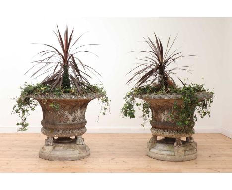 A pair of large composite stone garden planters,20th century, each of basket form, raised on paw feet and a shaped circular b
