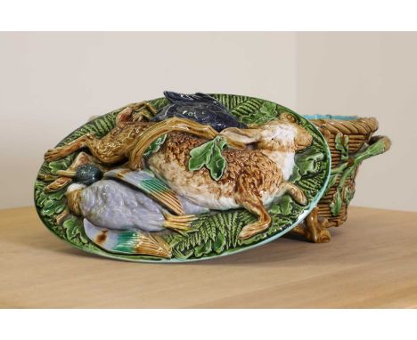 A Victorian Minton majolica game dish and cover, of oval form, the cover embellished with dead game in relief, on a basket fo