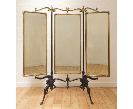 A cast iron and brass triptych cheval mirror, c.1900-1910, American, with scrolling foliate detail and raised on lion support
