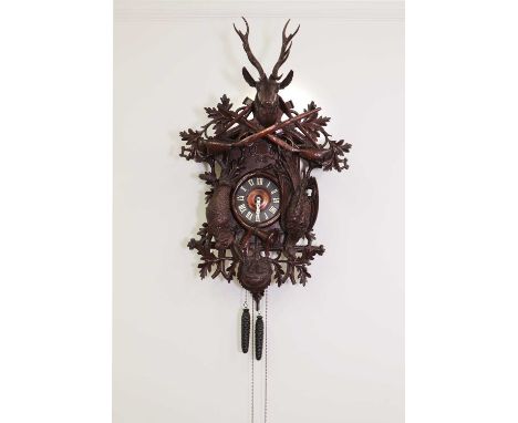 A large carved Black Forest wall-hanging cuckoo clock,the detachable top with a stag's head and two rifles, over hare and phe