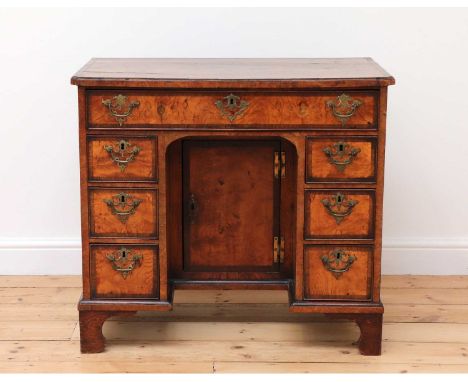 A George II burr elm and rosewood crossbanded kneehole desk,the top with re-entrant corners, over a long frieze drawer and si