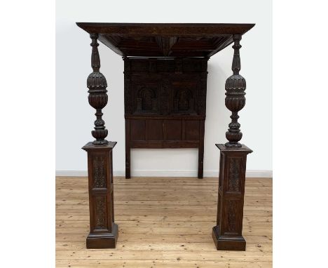 An oak four-poster bed, 17th century and later, with a panelled back, moulded top, with leaf carved cornice, the foot support