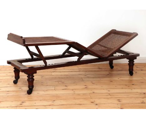 A Victorian caned campaign daybed,mid-19th century, with adjustable seat and raised on turned detachable legs with ceramic ca