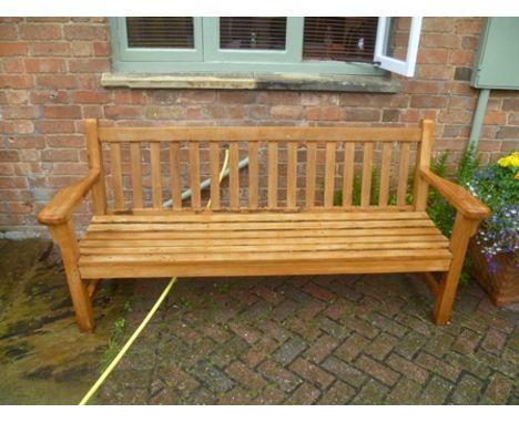 A teak slat built four-seater garden bench, of typical form and construction, approximately 6' long 