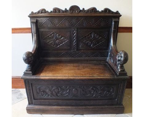 An Elizabethan design oak hall bench, having acanthus scroll and scallop frieze, above twin chip carved panel back, substanti