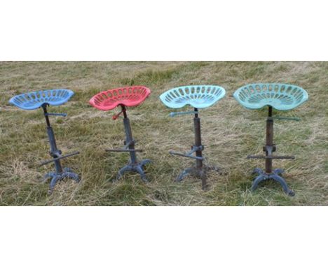 A set of four tractor seat bar stools, the painted cast iron seat on a screw adjustable support, with foot rest and four spla