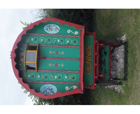 A bow top gypsy caravan, painted green with red edging, decorated with painted flowers and garden bird panels, inscribed "Den