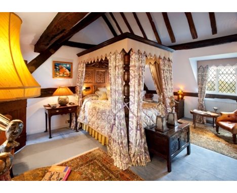 An oak four poster bed constructed from 17th century timbers and panels, the headboard with pair of foliate 'S' scroll panels