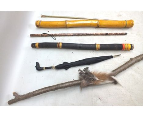 Two bamboo rain sticks, one 117cm high, a dog's head handled umbrella, walking stick, harpoon and tribal staff with fur, feat