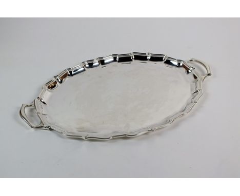 A two handled silver tray, Roberts & Belk, Sheffield 1988, of oval form with pie crust rim and two loop handles, 53cm wide, w