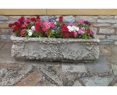 A reconstituted stone trough with fruiting vine decoration in the round, of waisted form, 100cm x 46cm x 33cm high 