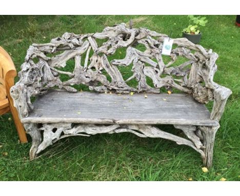 A rustic garden bench, assembled from gnarled branches, with plank seat, 1.39m wide, 86cm high 