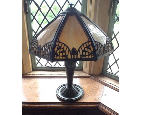 A Tiffany style table lamp, cast and painted metal umbrella shade with bell husk motifs and acanthus cap, inset eight panels 