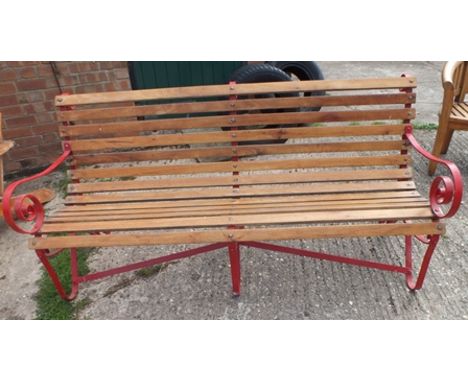 A wrought iron framed garden bench, red painted metal with scroll arms and back detail, with teak slats, 81cm wide, 87cm high
