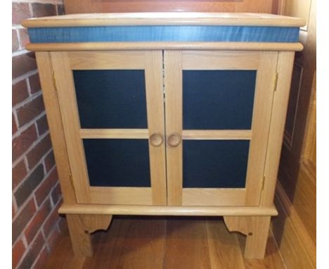 A contemporary craftsman made oak cabinet, having blue frieze, the double doors fitted black speaker mesh, turned knob handle
