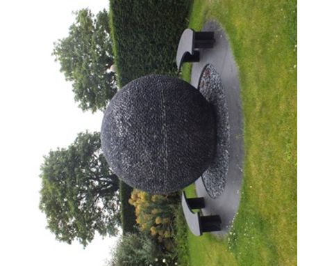 David Harber A 20th century garden water feature entitled "Dark Planet" being a sphere of black pebbles set in a circular bed