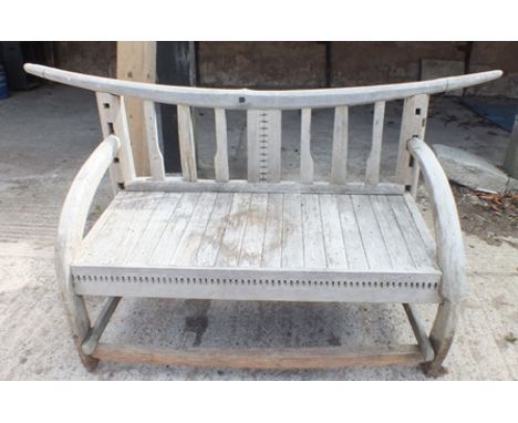 A rustic garden bench, having carved bow back, with arched arms and planked seat, 1.76m wide, centre height, 83cm 