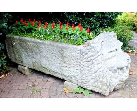 A 19th century hewn stone trough, one end carved with lion mask, open mouthed, with full mane, 60cm wide, 70cm high, approx 2