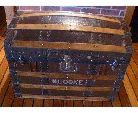 A dome topped trunk, circa 1900, wood and leather banded, with leather side fitted carrying handles, inscribed to the front; 