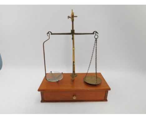A set of Victorian brass postal scales, raised on a mahogany base, with single frieze drawer containing a few weights.