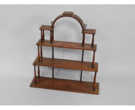 An Edwardian mahogany three tier wall shelf, of open architectural form, raised on turned columns, 74.5cm x 20cm x 83cm.