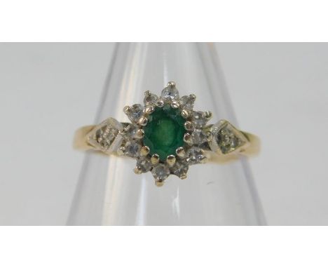 A 9ct gold emerald and diamond ring, the flower head setting with diamond set shoulders, size K, 2.2g.