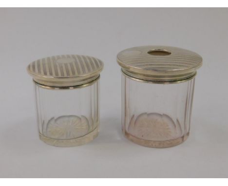 Two matching silver lidded glass toilet jars, the push on lids with engine turned decoration, Birmingham 1919, 8cm and 7.5cm.