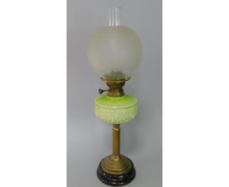 A late Victorian brass oil lamp, with moulded green glass reservoir and part etched globe shade, with chimney, 45cm high.