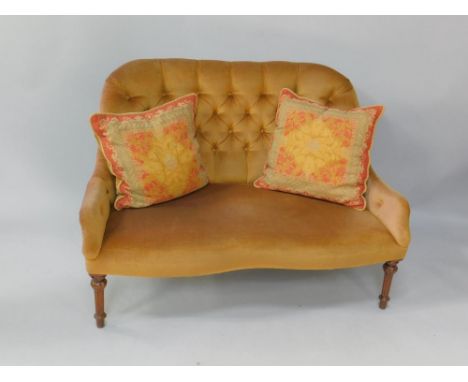 A Victorian mahogany two seater sofa, with button back gold upholstery and shaped stuffed seat, raised on turned and fluted l