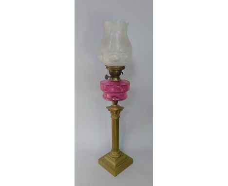A late Victorian oil lamp, with cranberry glass reservoir and Duplex burner, supported on a brass Corinthian column with squa
