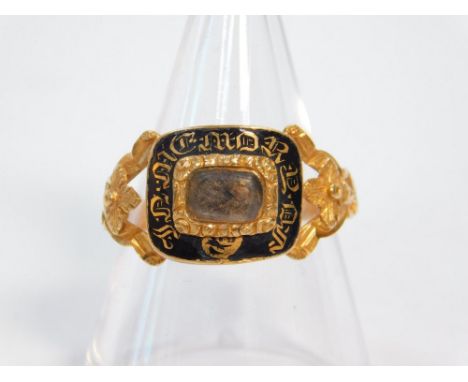 A Victorian gold and black enamel mourning ring, set centrally with woven hair, the shank with floral cast shoulders, verso e